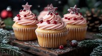 Festive vanilla cupcakes with pink frosting, topped with sparkly star decorations and cranberries, arranged on wooden board with pine branches and holiday decor.