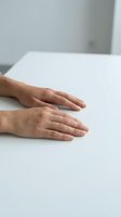 Two hands placed flat on clean white surface showing natural skin texture and relaxed positioning for healthcare or wellness concepts.