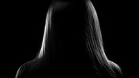 Dramatic silhouette of long straight hair illuminated from behind against dark background creates mysterious atmospheric portrait with strong contrast lighting effect.