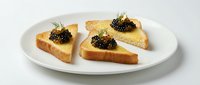 Toasted bread slices topped with creamy spread and black caviar garnished with fresh dill on white plate, suitable for appetizers and gourmet food styling.