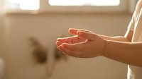Open cupped hands in warm sunlight streaming through window creating peaceful gesture of receiving or offering in soft natural lighting.