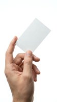 Male hand holding blank white business card on isolated background for mockup design and branding presentation.