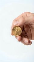 Hand holding golden coin with eagle design on white background for investment and wealth concepts.