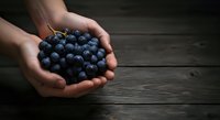 Hands holding fresh blueberries over dark wooden surface. Ripe berries in palms for food, nutrition, and healthy eating concepts.