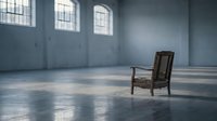 Empty industrial loft interior with vintage leather armchair and natural sunlight streaming through large windows creating dramatic shadows on concrete floor.