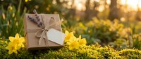 Eco-friendly gift box with blank tag and yellow daffodils on moss in golden sunlight, sustainable packaging concept for spring celebrations and holidays.