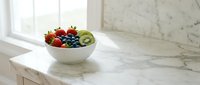 Fresh mixed berries and kiwi fruit in white bowl on marble countertop near window, healthy eating and nutrition concept for kitchen design.