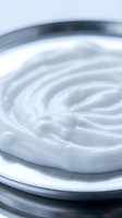 White cream swirl in bowl with smooth texture and circular motion pattern for skincare cosmetics and beauty product applications.