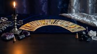 Mystical tarot cards spread in arc formation with burning candle, crystals and ornate cloth creating atmospheric fortune telling scene for spiritual guidance.