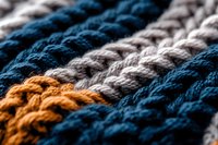 Macro view of colorful braided rope texture showing orange, blue and gray stripes in diagonal pattern. Close-up detail reveals woven fiber structure and depth.