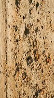 Weathered stone surface with natural holes and porous texture showing erosion patterns and rough mineral formations for architectural backgrounds.