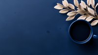Minimalist composition with blue ceramic coffee cup and white decorative leaves on deep navy background, creating modern aesthetic appeal.