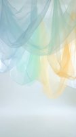 Soft translucent fabric layers in pastel blue, green and yellow tones creating ethereal flowing movement against light background for elegant design projects.