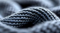 Close-up macro shot of gray knitted wool textile showing detailed texture and pattern of woven fabric fibers in soft focus. Suitable for fashion and craft backgrounds.