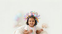 Young girl with dark hair and medium skin tone wearing white clothing, smiling at camera with colorful lollipop crown headpiece against soft blurred background for children's portraits and festive designs.
