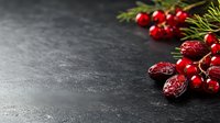 Fresh red cranberries and dried cranberry fruits with pine branch on dark stone background with copy space for text, winter holiday food concept.