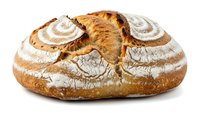 Freshly baked artisan sourdough bread loaf with decorative spiral scoring pattern and golden brown crust isolated on white background for bakery designs.