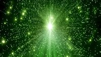 Bright green starburst explosion with glowing particles and light rays radiating from center against dark background, creating magical cosmic effect.