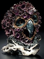 Artistic mineral formation featuring purple amethyst crystals and blue-green fluorite creating an abstract skull-like shape, mounted on white crystalline base against dark background.