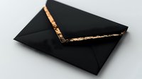 Black envelope with elegant gold foil accent in minimalist style on light background, luxury stationery for wedding invitations and special occasions.