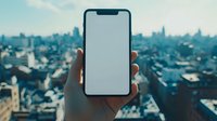 Modern smartphone with blank white screen held up against blurred urban cityscape background showing downtown skyline and buildings in soft blue tones.