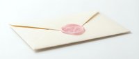 Closed cream envelope with pink wax seal and wooden stick on white background, suitable for wedding invitations, formal correspondence, stationery design.