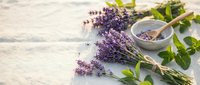 Fresh lavender bundles with mint leaves and mortar pestle on rustic wooden surface for natural aromatherapy and herbal medicine preparation.
