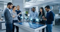 Diverse business team collaborating around interactive touchscreen table in modern office discussing digital workflow solutions and technology.