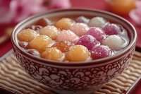 Colorful glutinous rice balls in sweet syrup served in traditional ceramic bowl, Asian dessert tangyuan for festivals and celebrations.