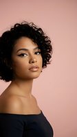 Young African American woman with curly hair and natural makeup posing against pink background for beauty and fashion photography.