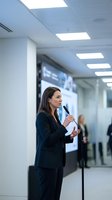 Professional businesswoman presenting at corporate conference with microphone in modern office environment for business communications.