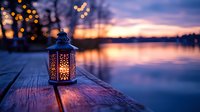 Decorative lantern glowing on wooden dock at twilight with bokeh lights reflecting on calm lake water during peaceful evening sunset.