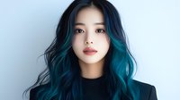 Young Asian woman with vibrant turquoise ombre hair wearing black against light background, looking directly at camera with natural makeup and serene expression.