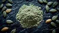 Green cardamom powder and whole pods scattered on dark stone surface, aromatic spice ingredients for cooking, baking and traditional beverages.