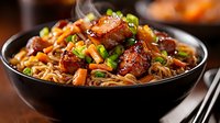 Glazed pork belly with stir-fried noodles, carrots, and green onions in black ceramic bowl. Asian cuisine with sweet and savory sauce garnished with chopped scallions.