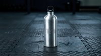 Stainless steel water bottle with carrying loop on dark textured surface, suitable for beverage packaging mockups and product advertising.