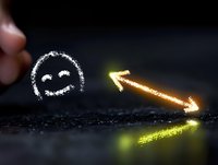 Glowing neon arrow points to chalk drawn happy face on dark background, creating optimistic business growth concept with light effects and reflection.