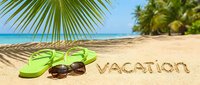 Tropical beach scene with green flip flops, sunglasses, and vacation written in sand under palm leaves, evoking summer holiday relaxation.