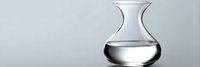 Clear glass carafe with liquid on gray background, minimalist composition showing transparency and reflection, isolated for design and commercial use.