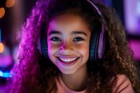 Young African American girl with curly hair wearing headphones smiles brightly in purple neon lighting, capturing genuine joy and modern lifestyle in gaming setup.