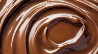 Swirling melted milk chocolate creates smooth glossy waves and ripples with rich brown tones and creamy texture, suitable for confectionery and dessert marketing.