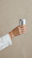 Hand holding aluminum beverage can against neutral beige background for product mockup and branding design projects.