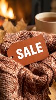 Cozy autumn sale tag on warm knitted sweater near fireplace with tea cup and fall leaves, seasonal discount concept.