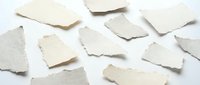 Torn paper pieces scattered on white background creating abstract composition for creative projects and artistic designs.