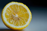 Fresh yellow lemon cut in half showing detailed pulp segments and white pith on dark background, macro food photography with selective focus.