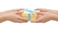 Two pairs of hands exchanging a yellow gift box with a blue ribbon bow, isolated on white background, symbolizing giving and celebration.