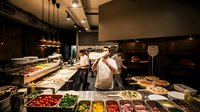 Professional chefs preparing fresh dishes in modern restaurant kitchen with colorful ingredients and contemporary lighting for culinary business.