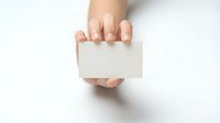 Female hand holding blank white business card mockup on clean background for branding and corporate identity design projects.
