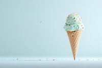 Mint ice cream scoop with colorful sprinkles in waffle cone against pastel blue background. Minimalist summer dessert composition with copy space.