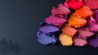 Colorful makeup eyeshadow palette with vibrant shades from purple to orange creating rainbow spectrum for beauty and cosmetics applications.